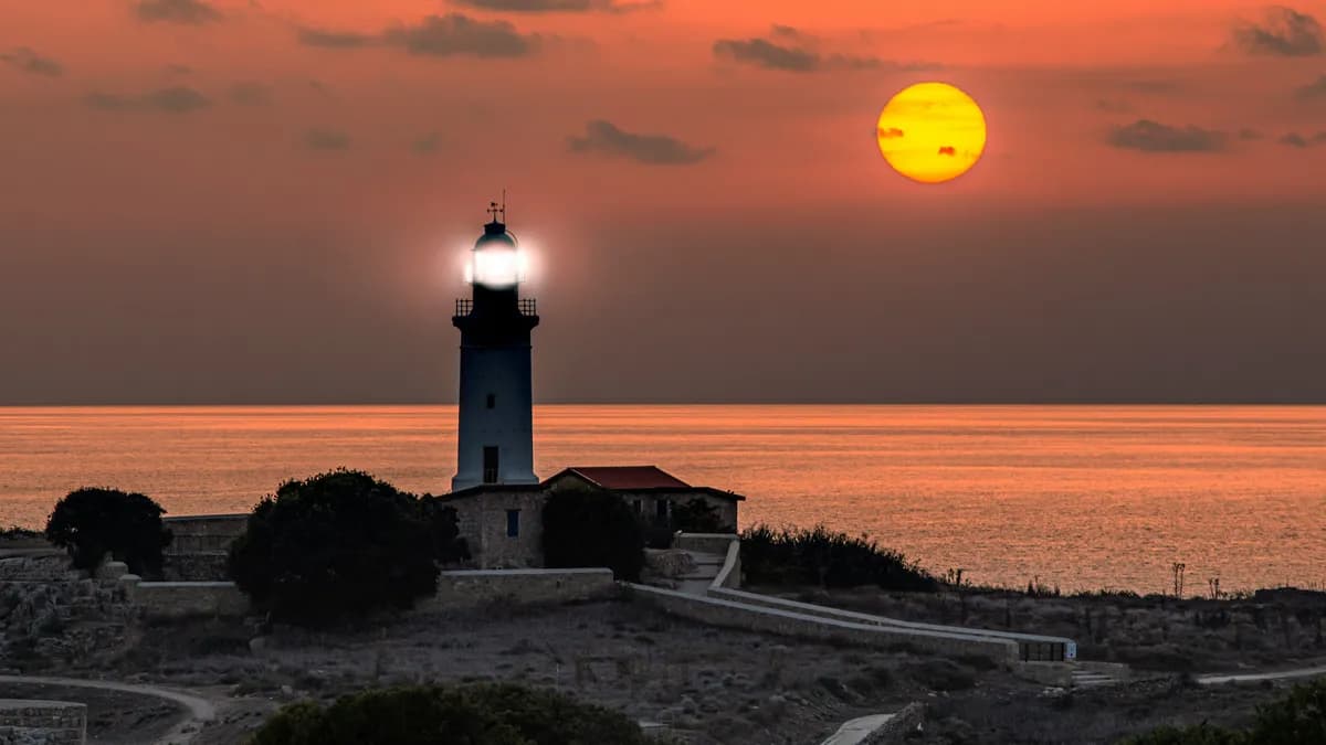 a lighthouse with a bright yellow sun in the background